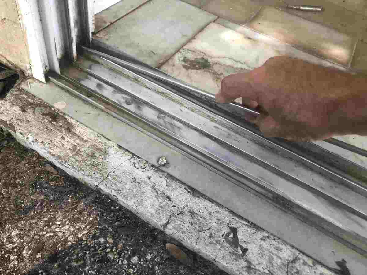 Damaged aluminum sliding door bottom track being repaired